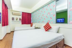 two beds in a room with a wall with a window at Newrise Hotel in Kaohsiung
