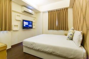 um quarto de hotel com uma cama e uma televisão em Newrise Hotel em Kaohsiung