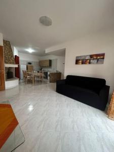 a living room with a black couch and a kitchen at Appartamento Sud Sardegna, Cagliari Elesar'sHome in Capoterra