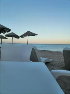 una mesa y sillas con sombrillas en la playa en Appartamento Sud Sardegna, Cagliari Elesar'sHome en Capoterra