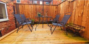 a patio with chairs and a table on a wooden floor at Private Room in Modern House near Nottingham in Nottingham