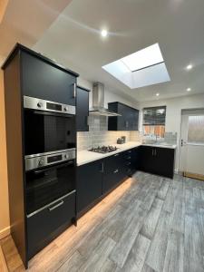 een keuken met zwarte kasten en een fornuis met oven bij Elegant Large Room in Beckenham