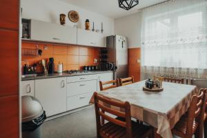 una cocina con mesa y sillas y una cocina con armarios blancos. en Willa Baca, en Duszniki-Zdrój
