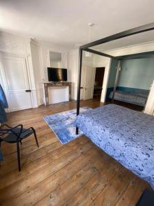 a bedroom with a bed and a chair on a wooden floor at VICTOR HUGO in Amiens