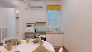 eine Küche mit einem weißen Tisch und Stühlen sowie einem Tisch und einer Küche in der Unterkunft The Koukaki Residence in Athen
