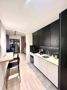 a kitchen with white counters and black cabinets at Belgrade Waterfront- Libera in Belgrade