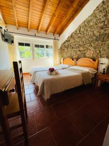 a bedroom with two beds and a stone wall at Hotel Restaurante La Navaliega in Oviedo