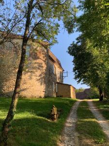 an old stone building with a dirt road next to a tree at Château de Monsac in Monsac