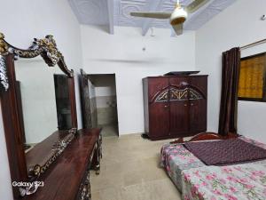 a bedroom with a bed and a dresser and a mirror at SYED FAMILY REST HOUSE in Karachi