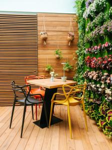 Etna Cottage Charming Bed and breakfast في نيكولوسي: طاولة وكراسي عليها نباتات على الحائط