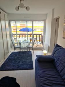 a living room with a couch and a table at Charmant studio dans résidence front de mer in Cabourg