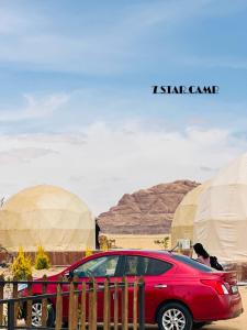 a red car parked in front of some tents at 7star camp in Wadi Rum