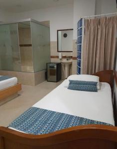 1 dormitorio con 2 camas, lavabo y espejo en ApartaHotel Montes Medellin, en Medellín