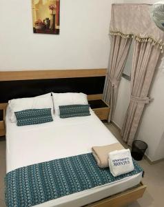 1 dormitorio con cama blanca y almohadas azules en ApartaHotel Montes Medellin, en Medellín