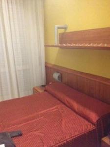 una camera con un letto rosso e una coperta rossa di hotel bengasi a Rimini