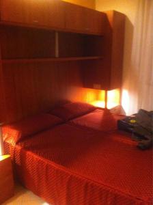 a bedroom with a bed with a red comforter at hotel bengasi in Rimini