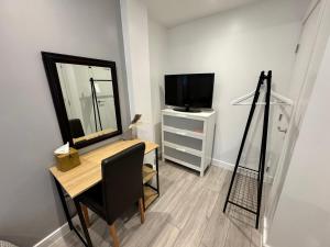 een kamer met een bureau met een spiegel en een televisie bij Cosy Budget Room in Beckenham