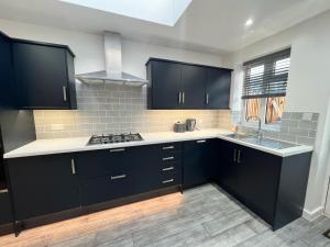 uma cozinha com armários pretos e bancadas brancas em Cosy Budget Room em Beckenham