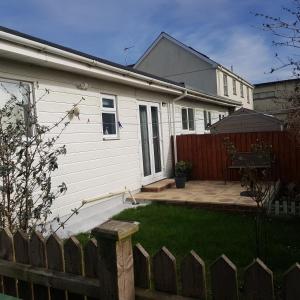 a white house with a fence and a yard at Rogie's place in Woolacombe