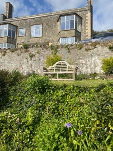 a bench sitting in front of a brick building at 2 bed apartment overlooking North Sands beach in Salcombe