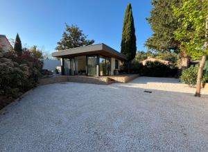 a house with a gravel driveway in front of a building at Lodge Valbelle, maison indépendante avec jacuzzi, Love room in Tourves