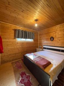 a bedroom with a large bed in a wooden room at Origjina Farm in Përmet