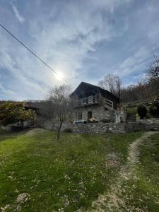 a stone house on a hill with a grass yard at Origjina Farm in Përmet