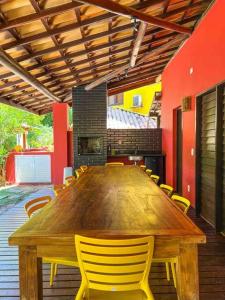 a large wooden table in a room with yellow chairs at Casa do Lord - Natú in Mata de Sao Joao