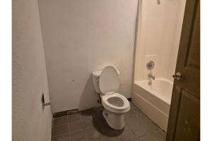 a bathroom with a white toilet and a bath tub at OYO Hotel Vienna I-75 in Vienna