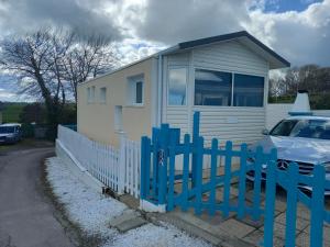 une maison blanche avec une clôture bleue et une voiture dans l'établissement MAISON AVEC VUE MER, à Saint-Côme-de-Fresné