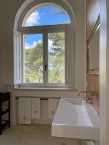 Łazienka z dużym oknem i białą umywalką w obiekcie Villa Di Noi w mieście Arnesano