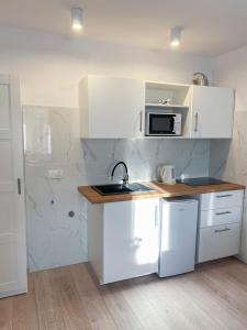 a white kitchen with a sink and a microwave at Apartament i pokoje gościnne Danuta in Ostrowo
