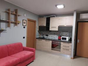 a living room with a red couch and a kitchen at Nico's Home - Rho Fiera Milano in Pero +12 photos