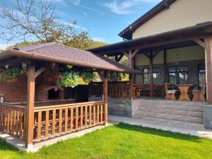 a wooden pavilion with a deck in front of a house at Pensiunea Eden in Budureasa