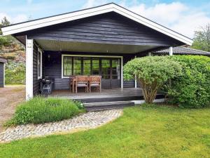 una casa negra con una mesa y sillas en un porche en 7 person holiday home in Bovallstrand en Bovallstrand