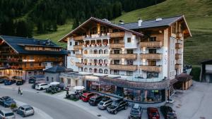 un gran edificio con coches estacionados en un estacionamiento en Hotel Salzburger Hof Zauchensee, en Zauchensee