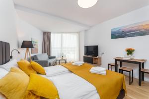 a bedroom with a large bed with a yellow blanket at Apartament Prywatny Seaside Park 649 in Kołobrzeg
