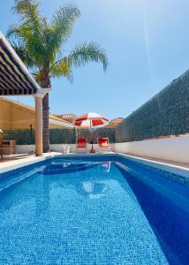 una piscina con 2 sillas y una sombrilla en 2 bedroom villa with private swimming pool, en San Juan de los Terreros