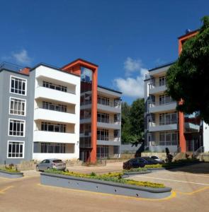 an apartment building with cars parked in a parking lot at WHITE LOTUS EXECUTIVE APARTMENT in Meru