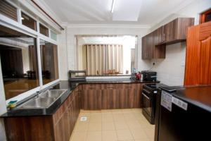a kitchen with wooden cabinets and a sink at WHITE LOTUS EXECUTIVE APARTMENT in Meru