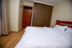 a bedroom with a large white bed and a wooden door at WHITE LOTUS EXECUTIVE APARTMENT in Meru