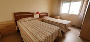 two beds with striped sheets in a room at Apartament Roqueta in Palamós