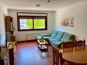 sala de estar con sofá azul y mesa en Apartamento con jardín y piscina temporada verano privados, en Samieira