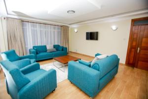 a living room with two blue couches and a table at WHITE LOTUS EXECUTIVE APARTMENT in Meru