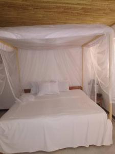 a bedroom with a white bed with a canopy at la villa sur la plage in Palmarin