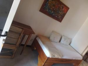 a small bedroom with a bed and a painting on the wall at la villa sur la plage in Palmarin