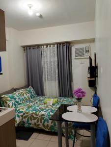 Zafreen Staycation/CONDOTEL في مانيلا: غرفة بها سرير وطاولة عليها زهور