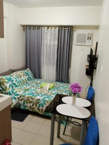 una habitación con una cama y una mesa con flores. en Zafreen Staycation/CONDOTEL, en Manila