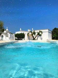 ein großer Pool mit blauem Wasser vor einem Gebäude in der Unterkunft VITA VIVET TRULLO in San Michele Salentino