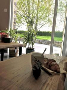 eine Kaffeetasse und ein Croissant auf einem Holztisch in der Unterkunft Une Parenthèse de Sérénité, séjour avec accès au SPA illimité in Vitré